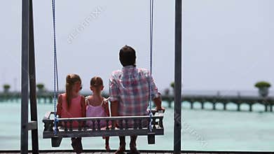 Adorable little girls and young father on swing