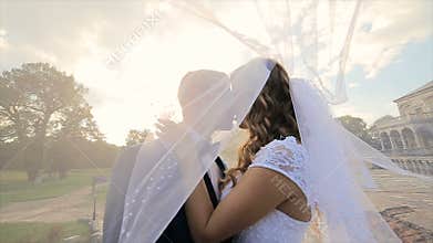 Groom kisses the bride under a veil