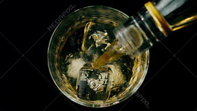 Barman pouring whiskey with ice cubes in the glass on wood table, view top, time of relax