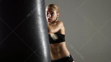Beautiful boxer girl has an attempt on punching bag. Studio