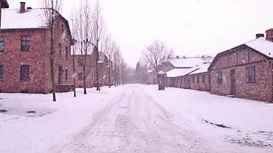 Steadicam shot of Auschwitz Birkenau, German Nazi concentration and extermination camp. Barracks in falling snow. 4K