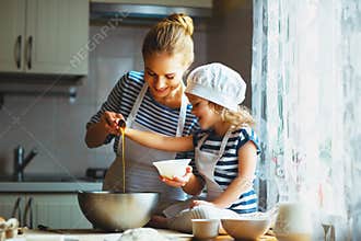 Happy family in kitchen. mother and child preparing dough, bake