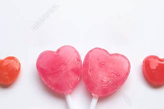 Pink Valentine`s day heart shape lollipop small red candy in cute pattern on empty white paper background. love concept. top view.