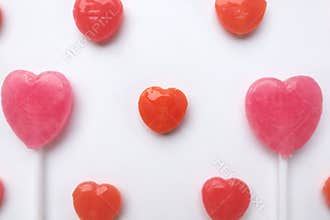 Pink Valentine`s day heart shape lollipop small red candy in cute pattern on empty white paper background. love concept. top view.