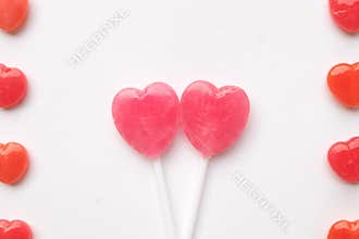 Pink Valentine`s day heart shape lollipop small red candy in cute pattern on empty white paper background. love concept. top view.