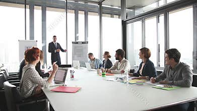 Young director giving presentation to colleagues in conference room