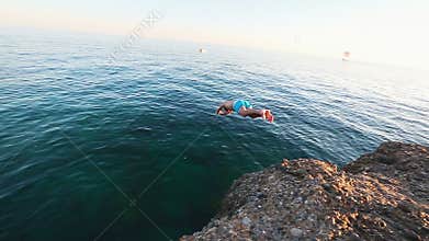Man jumping off of the cliff and dives into the Mediterranean sea