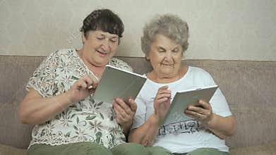 Two old women holding the silver digital tablets
