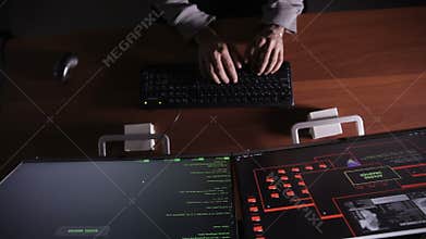 Hacker hands cracking code using computers in dark room.