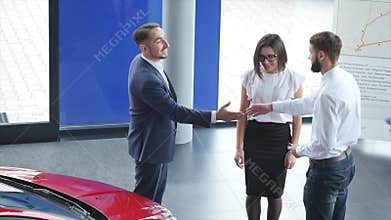 Top view of young male consultant and buyers signing contract for new car in auto show. Concept for car rental