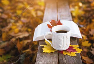 Hot coffee and red book with autumn leaves on wood background - seasonal relax concept