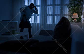 Burglary or thief breaking into a home at night through a back d