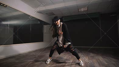 Female dancer in white shirt, black trousers and black cap showing jazz modern dancing. Girl is expressively dancing and