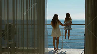 Mom and daughter go to the balcony with the sea view from the guest room