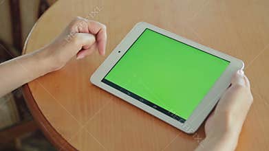 Woman looking at tablet computer with green screen in cafe