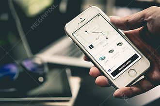 Business man is using Uber application on his iPhone.