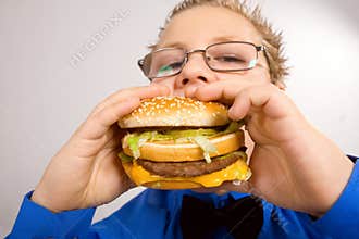 Young school boy eating hamburger
