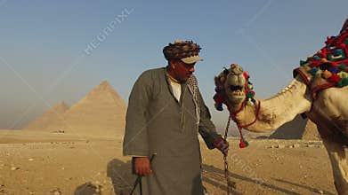Local man kissing his camel in front of Giza pyramids