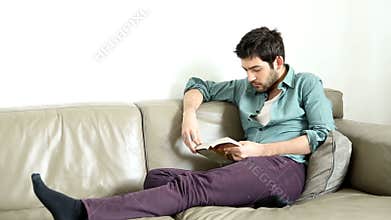 Handsome man sitting on comfortable couch reading book