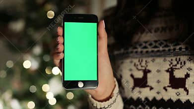 Close-up of female hands touching of smartphone. Green screen Chroma Key. Close up. Tracking motion. with blur christmas