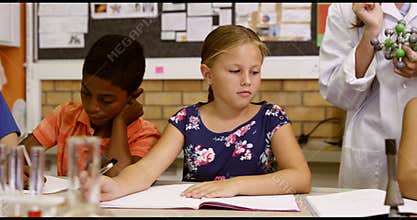 Teacher assisting school kids with molecule model in classroom