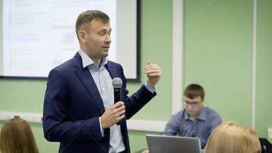 The teacher gives lectures on economics in college. With microphone in hand and with the help of gestures, he conveys to