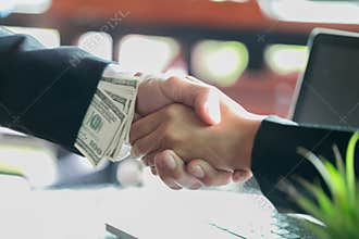 Corrupted businessman sealing the deal with a handshake and receiving a bribe money, anti bribery and corruption concepts
