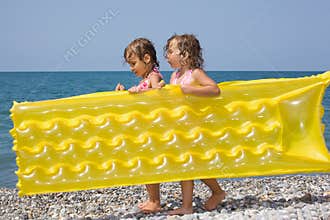 Two girls bearing in hands inflatable mattress