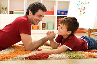 Happy kid and his father arm wrestling