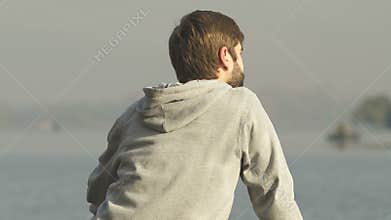 Pacified man sitting near water enjoying awesome view, calmness and inspiration