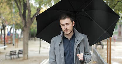 Sad man walking alone in a rainy day of winter