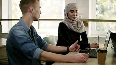 Close up footage of multiracial business people meeting in modern bright office at wooden table. Young caucasiam man in