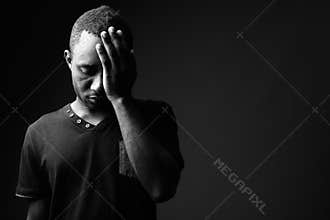 Frustrated young African man having headache in black and white