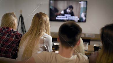 Young people sitting on sofa and watching TV