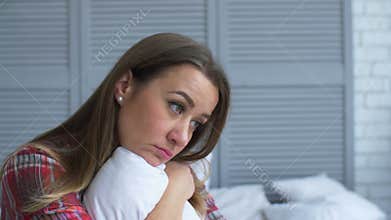 Upset lonely woman hugging pillow in problems