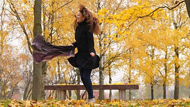 Happy woman crazy dancing in autumn park, bright colourful maple trees