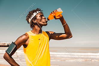 Running man at the beach drinking energy drink