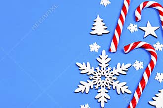 Christmas candy cane lied evenly in row on blue background with decorative snowflake and star. Flat lay and top view