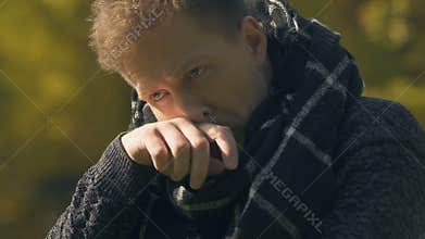 Man in scarf coughing outdoor, getting sick with flu on cold weather, closeup