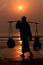 Silhouette of worker walking on the beach during sunset
