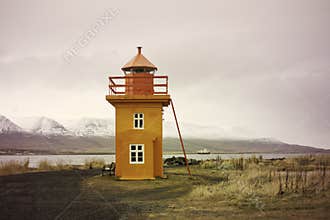 Orange Icelandic Lighthouse against mountain background
