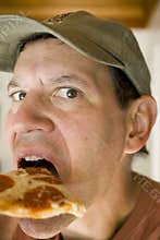 Man in Baseball Cap Eating Pepperoni Pizza