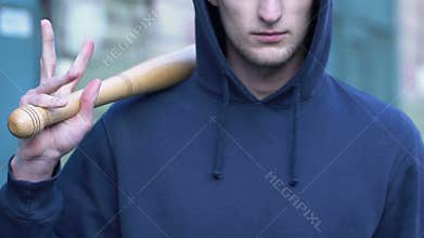 Aggressive man holding baseball bat ready to attack, street groupings of bully