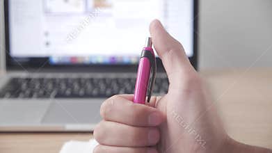 Extreme closeup of a man`s hand clicking his pen as if bored or nervous at work