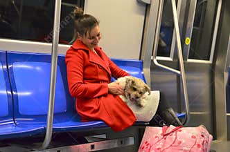 Happy young woman dressed in red coat, with small cute dog