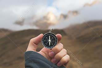 A male Hiker is looking for a direction with a magnetic compass in the mountains in the fall. Point of view shot. Man`s