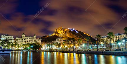 Night view of View of Alicante port with yachts against Castle Santa Barbara on Mongo mount in background.