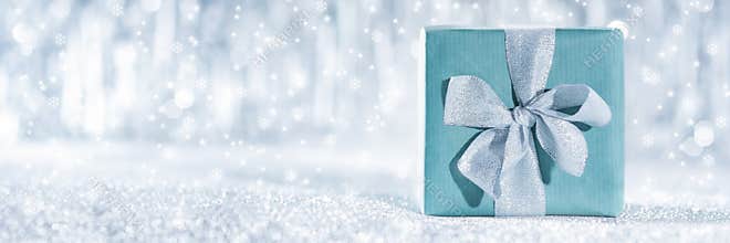 Beautiful wrapped christmas gift with defocused christmas lights in the background. Christmas banner.