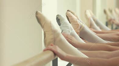 Close up legs of ballerinas at barre.