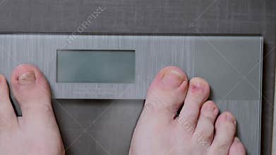 Male feet on glass scales, men`s diet, body weight